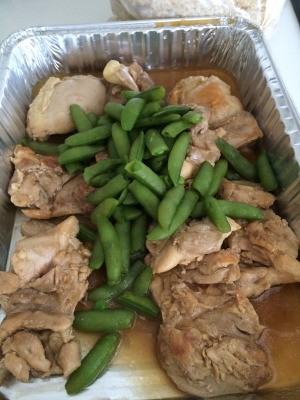 Chicken with Chinese brown sauce in serving dish with green beans.