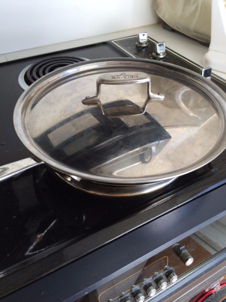 Chicken cooking in a covered pan.