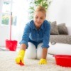 Woman on hands and knees scrubbing white carpet