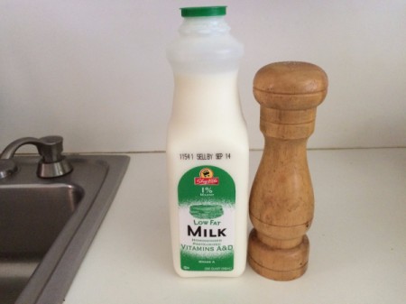 A bottle of milk next to a salt shaker.