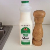 A bottle of milk next to a salt shaker.