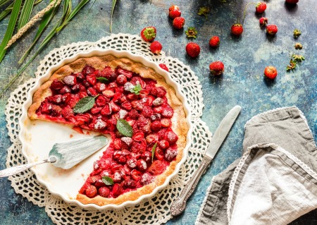 Strawberry Pie with several pieces missing surrounded by ripe strawberries