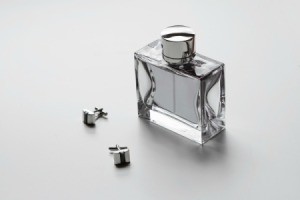 Bottle of men's cologne and cufflinks on a white surface