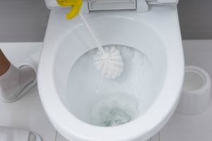 Toilet with lime deposits being cleaned with toilet brush