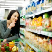 Woman leaning on her cart thoughtfully at the grocery store
