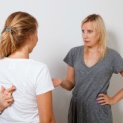 Girl arguing with her mother.  Mother is holding her hand out, girl has her fingers crossed behind her back