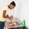 Woman using a plunger on a kitchen sink