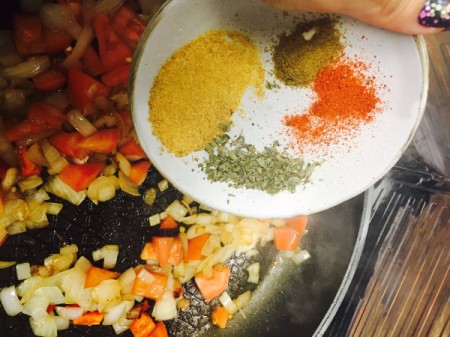 Adding spices to sauteed vegetables.