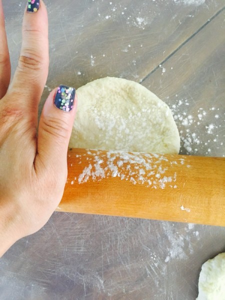 A piece of dough being rolled out for an empanada.