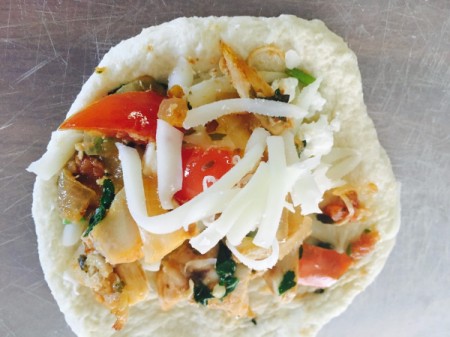 A filled empanada, ready for folding.