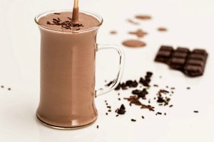 Glass of chocolate beverage with shaved chocolate and chocolate bar in the background