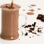 Glass of chocolate beverage with shaved chocolate and chocolate bar in the background