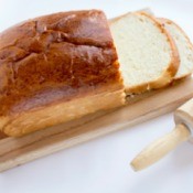 Loaf of bread with rolling pin on white background