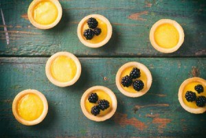 Several lemon curd tarts on a antiqued painted table