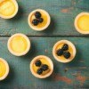 Several lemon curd tarts on a antiqued painted table