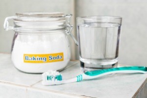 Toothbrush, jar labelled "baking soda" and a cup of water