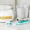 Toothbrush, jar labelled "baking soda" and a cup of water