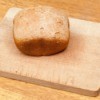 Loaf of bread machine bread that has not risen on a cutting board.