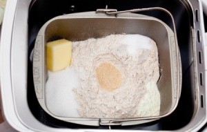 Interior of a bread machine full of ingredients including whole wheat flour