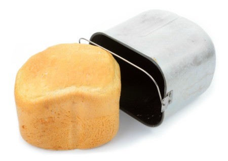 White loaf of bread machine bread laying next to a bread machine pan