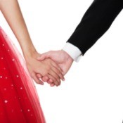 Close up of couple holding hands. Boy is in suit, girl is in a red sparkly party dress
