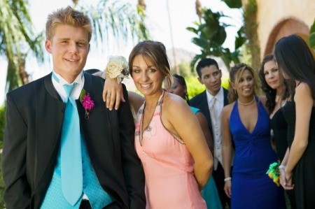 Friendly teen couple pose casually for picture at a school dance