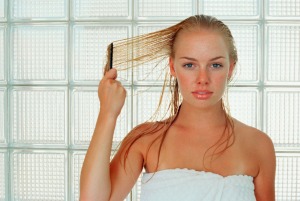 Woman in towel combing wet blond hair