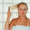 Woman in towel combing wet blond hair
