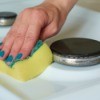 Woman's hand cleaning an enamel cooktop