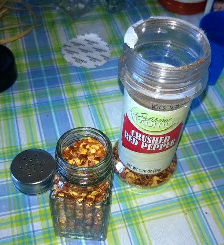 small shaker spice bottler filled with red pepper flakes from a larger container