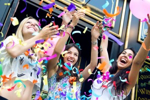 Teen girls throwing bright confetti outside