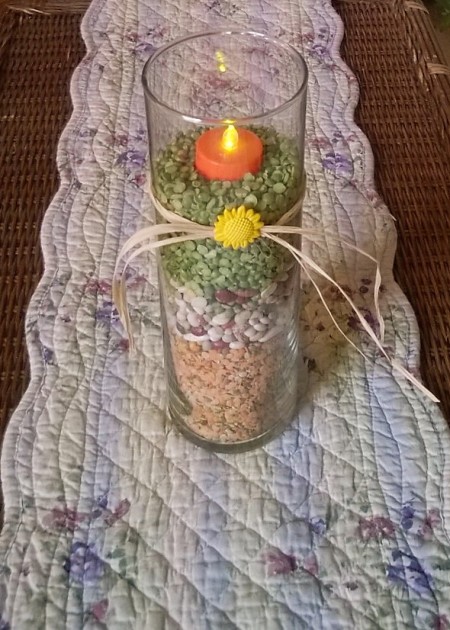 Candle vase filled with dried beans and peas.