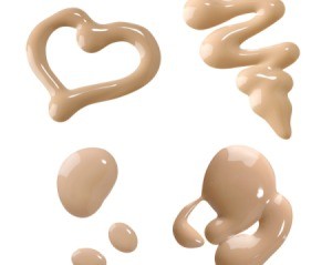 Puddles of liquid foundation makeup on a white background.  One is shaped like a heart.