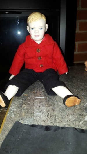 male doll wearing red coat and black pants