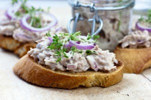 Creamed tuna on slices of toast garnished with herbs and red onion