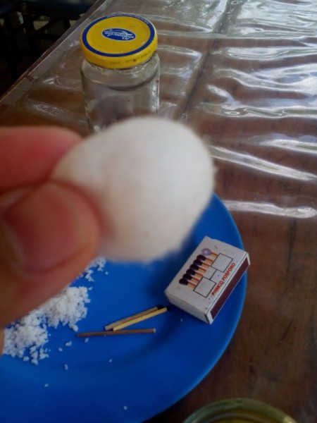 Readying a cotton ball to fashion a wick.