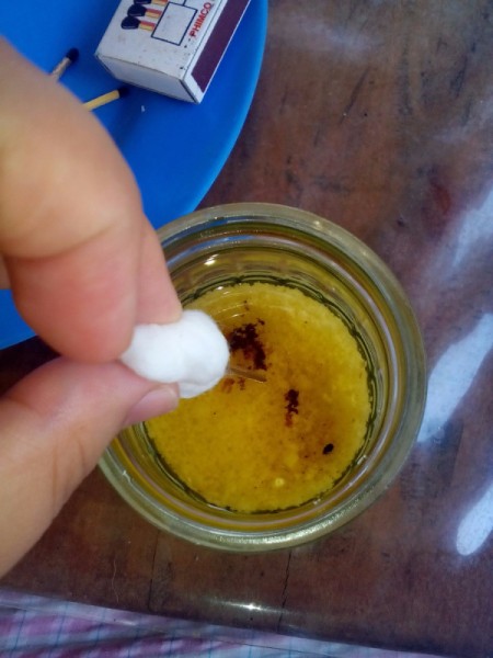 Inserting the cotton ball wick into the jar.