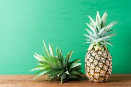 Pineapple and top of pineapple against green background
