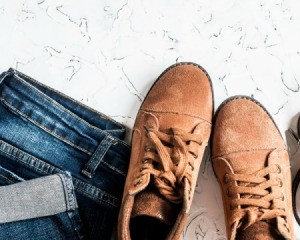 A pair of suede boots next to a pair of folded jeans