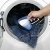 Powdered detergent being placed in front loader washing machine with jeans