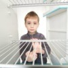 Young boy looking into empty fridge with sad expression