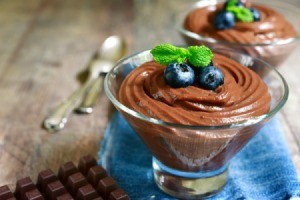 Diet chocolate pudding topped with blueberries in a glass serving cup