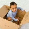 Young boy in diapers drawing on the inside of a box with a crayon