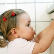 Toddler pressing up against the front of a dishwasher
