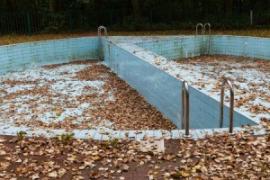 Abandoned empty outdoor swimming pool filled with leaves