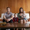 Family posed on sofa in front of wall with wood paneling