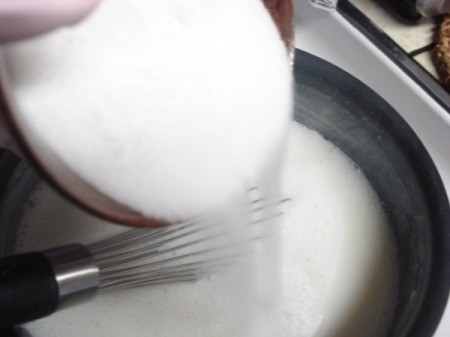 Adding sugar to the boiling milk mixture.