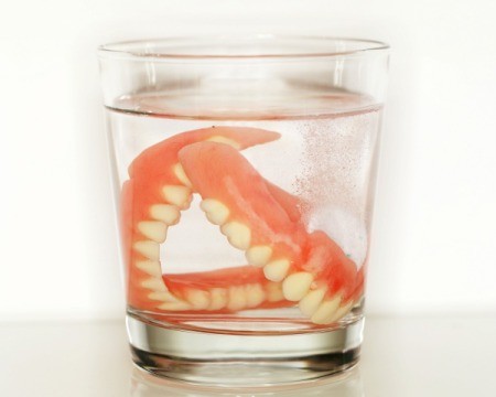 Pair of dentures in a glass of clear liquid