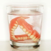 Pair of dentures in a glass of clear liquid