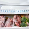 Bottom drawer freezer packed full of meats and broccoli